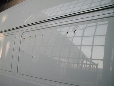 A van without liners showing damage to the wall